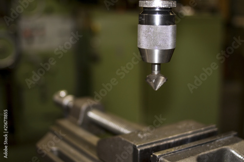 Industrial workshop with classic green drill machine for metal craft work with exchangeable countersink drill bit