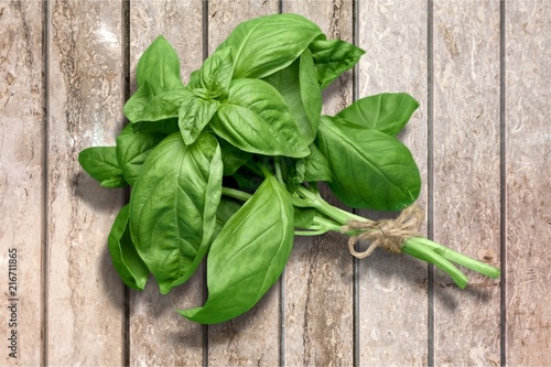 Green basil leaves on wooden background