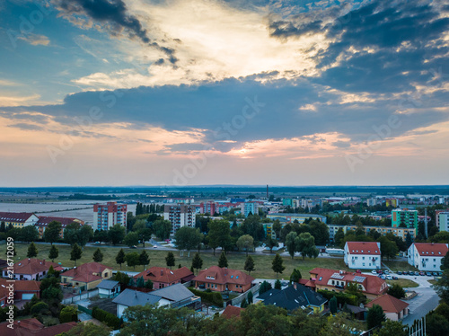 Above the town with dramatic sky and clouds. Green trees with fresh color.