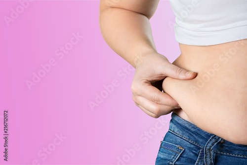 Woman's hand holding excessive belly fat
