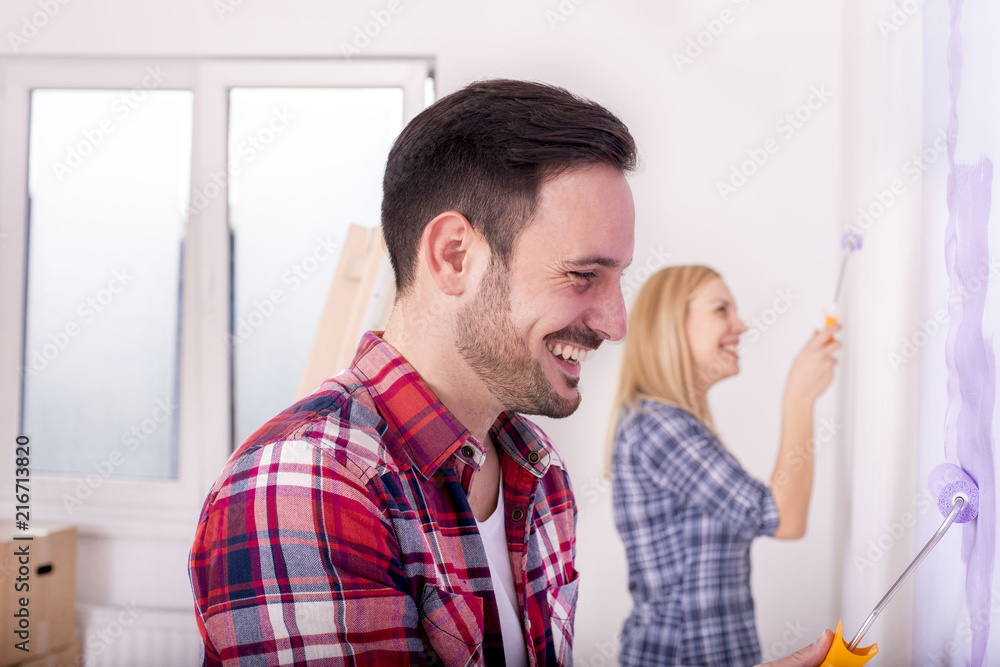 Fototapeta premium Couple painting a wall and doing repair at home together