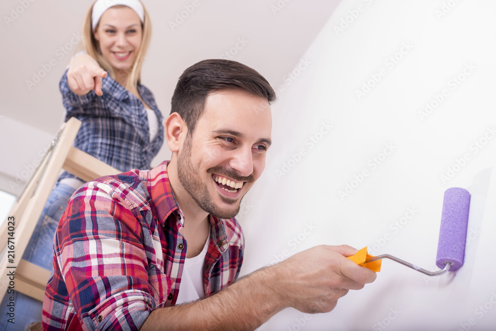 Couple painting a wall and doing repair at home together