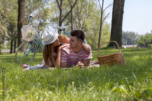 Beautiful couple lying in a meadow and enjoying picnic day together