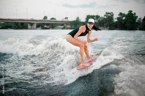 Young active girl riding on the wakesurf on the bending knees