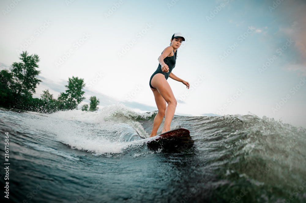 Side view young active girl riding on the wakesurf