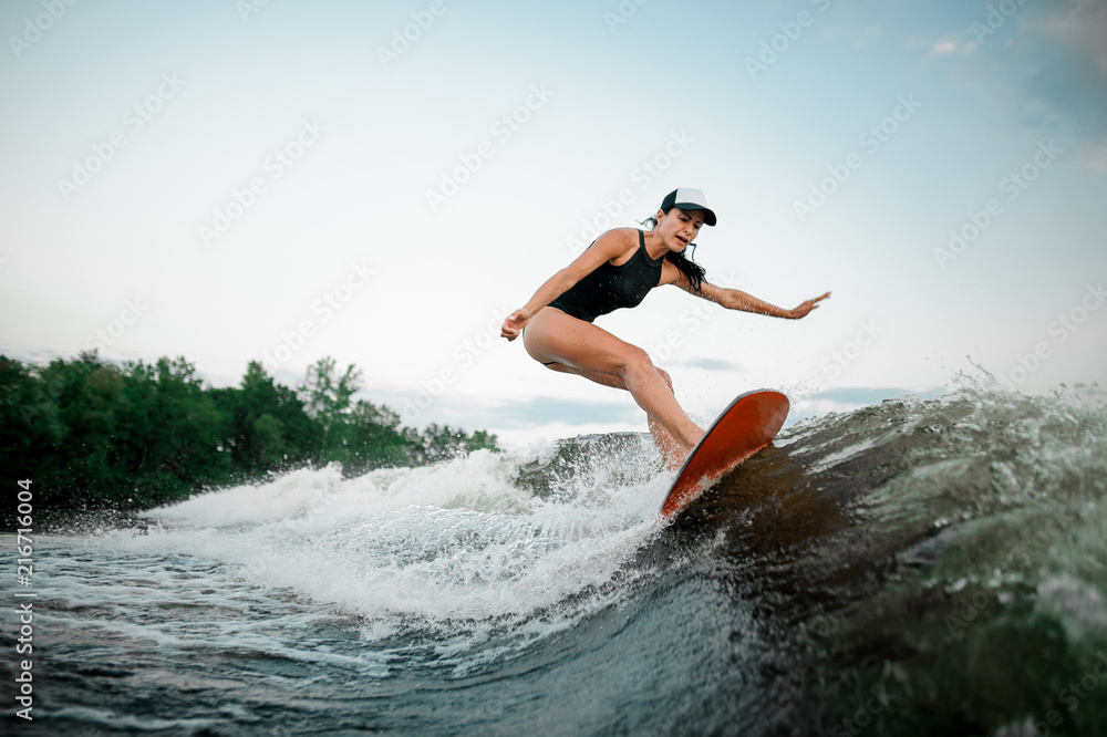 Young attractive girl riding on the orange wakesurf