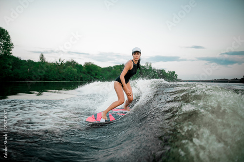 Young attractive woman riding on the orange wakesurf on the river © fesenko