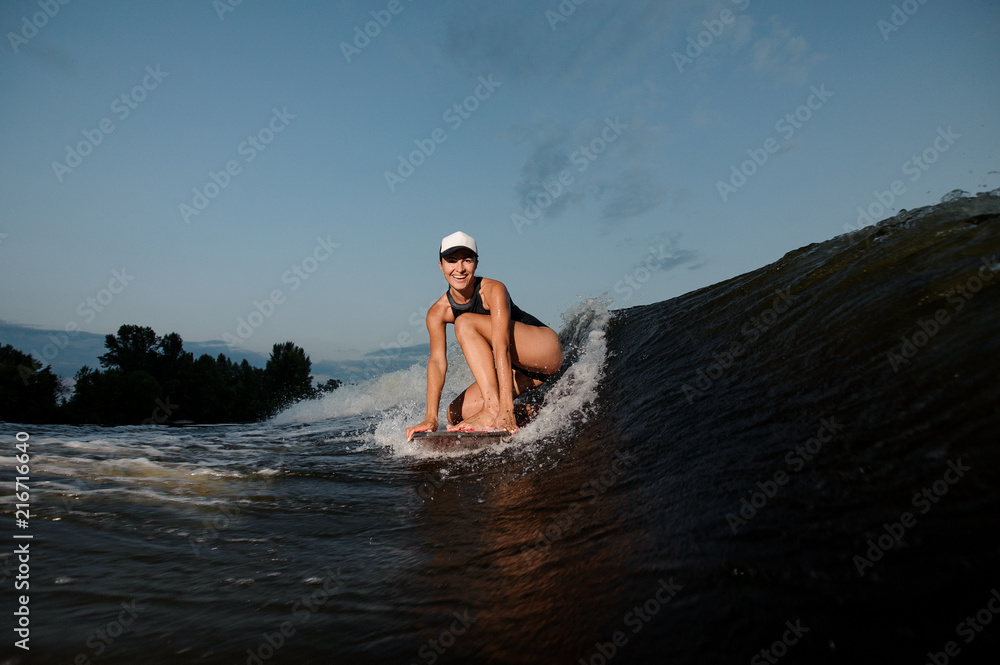 Attractive woman standing on the one knee on the wakesurf