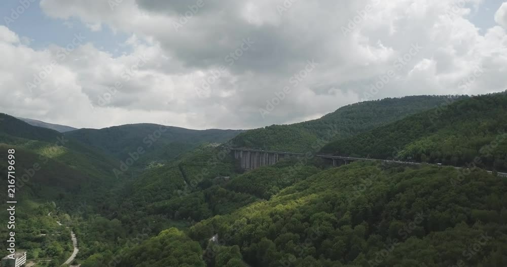 Drone shots of a bridge along a highway between a green forest. All shot in 4K and beautifully color graded to fit into any scene. Images show a grand bridge, forest and cars passing by. Drone shots of a bridge along a highway between a green forest. All shot in 4K and beautifully color graded to fit into any scene. Images show a grand bridge, forest and cars passing by.