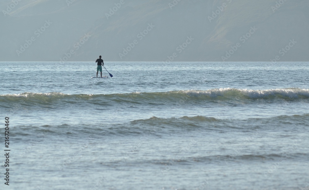 Homme sur une planche à rame en bord de mer