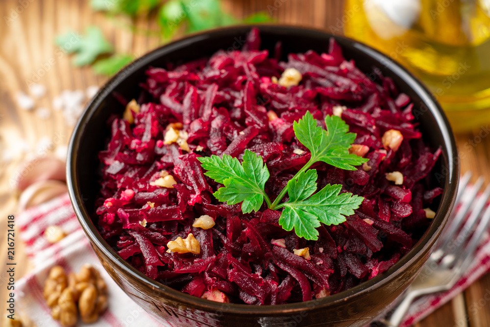 Beetroot salad with wallnuts and garlic in bowl on wooden table Beetroot salad with wallnuts and garlic in bowl on wooden table