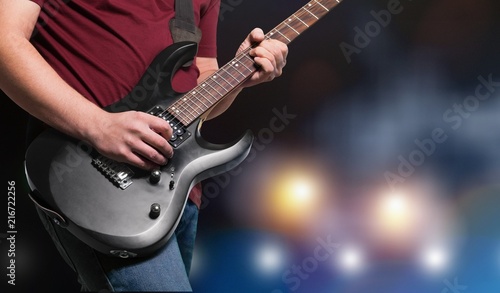 Male Guitarist playing music on dark background