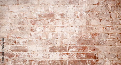 Warm red and white horizontal brick wall. Old uneven textured surface on a building in the city. Urban background with worn white painted bricks.