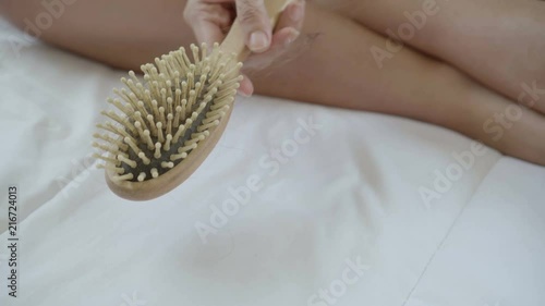 Woman hand pulling her hair fall from a comb wooden comb after hair combing.