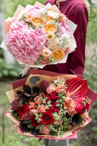 Two Beautiful summer bouquet. Arrangement with mix flowers. Young girl holding red and pink flower arrangements . The concept of a flower shop. Content for the catalog photo