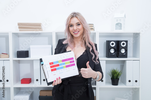 A beautiful girl smiles and holds the company's development schedule in her hands