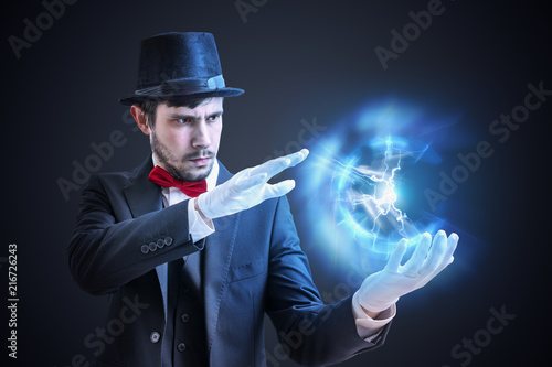 Magician or illusionist is showing bright plasma ball radiating light rays.