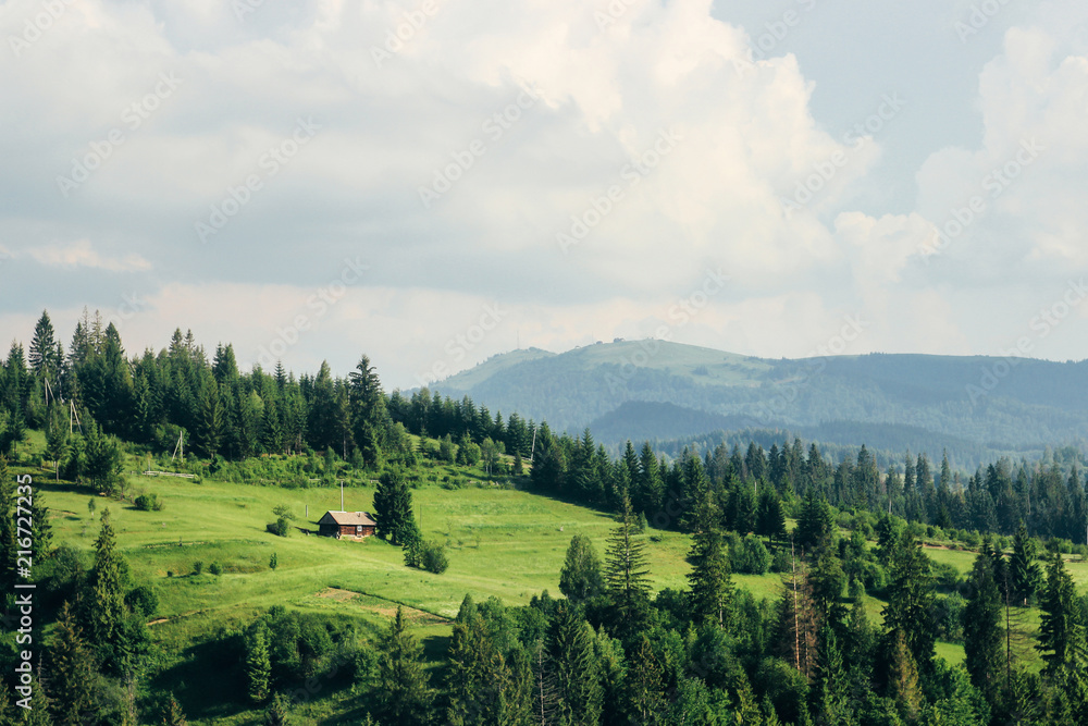 old wooden house and trees on top of hill mountains in sunny summer on background of sky and clouds old wooden house and trees on top of hill mountains in sunny summer on background of sky and clouds