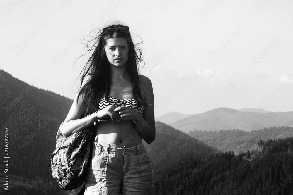 Obraz premium happy beautiful girl hipster traveling on top hill on background of amazing sky and mountains in summer, black and white