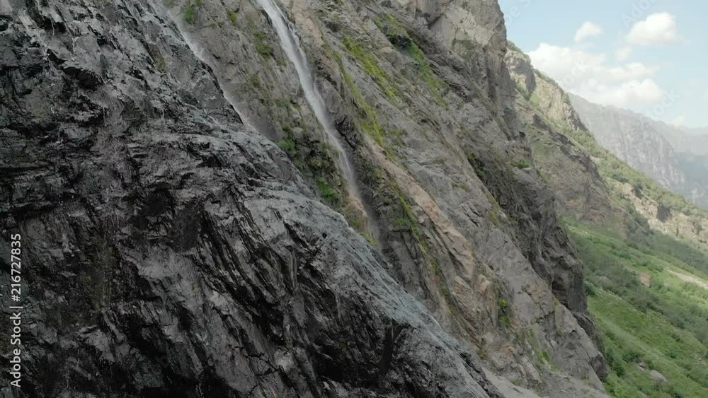 Tracking and top shot Air shot from a stream of water splashing waterfall on a rock wall in the Caucasus Mountains. Around the jet of the waterfall Tracking and top shot Air shot from a stream of water splashing waterfall on a rock wall in the Caucasus Mountains. Around the jet of the waterfall