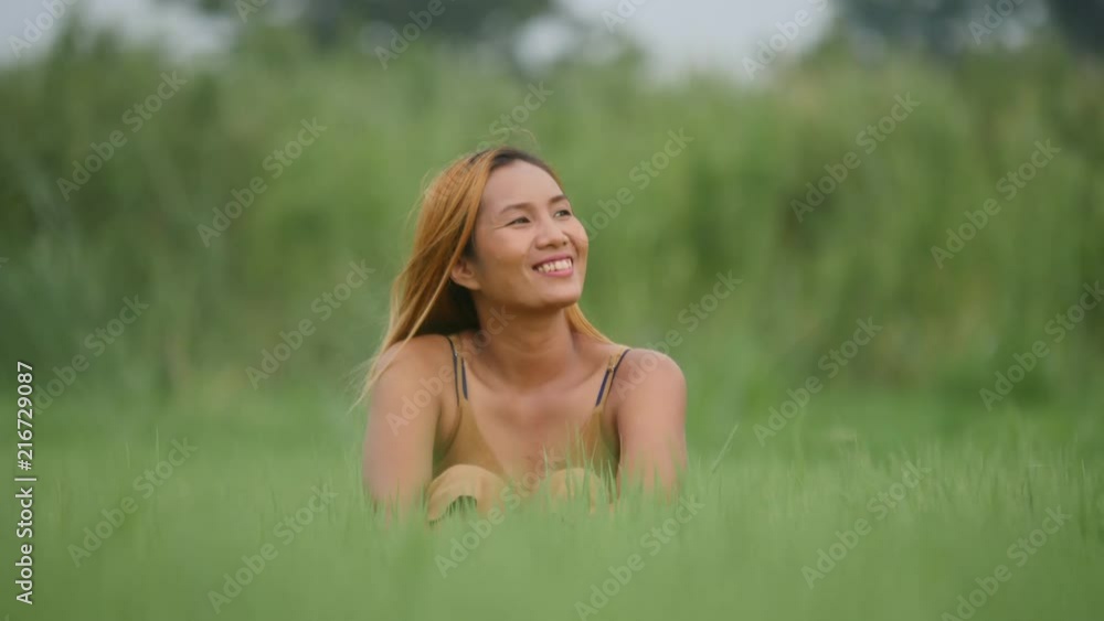 Joyful Woman Sitting on the green field and raising her hand refresh life Joyful Woman Sitting on the green field and raising her hand refresh life