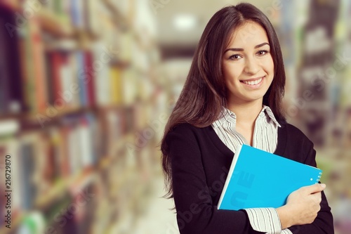 Young smiling woman holding blue notebook