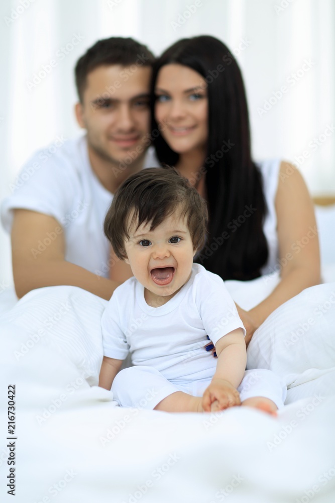 Happy couple and son sitting in bed