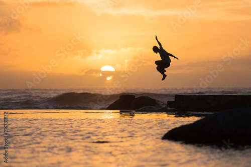 Silhouette of Man Jumping into the Water at Sunset