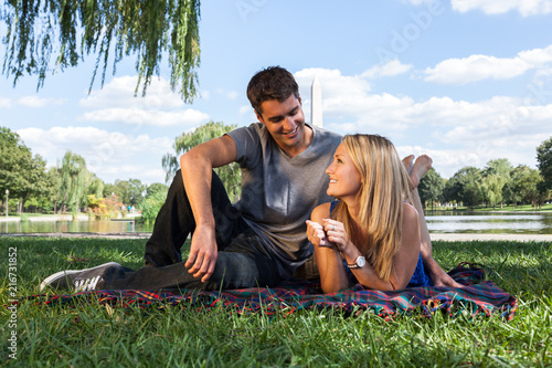 Smiling Young Couple Enjoying Picnic with Washington Monument in Background