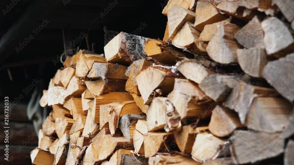 A woman's hand takes a birch dry chipped log from a woodpile. Someone is going to burn a tree to heat a house or to cook food. A woman's hand takes a birch dry chipped log from a woodpile. Someone is going to burn a tree to heat a house or to cook food.