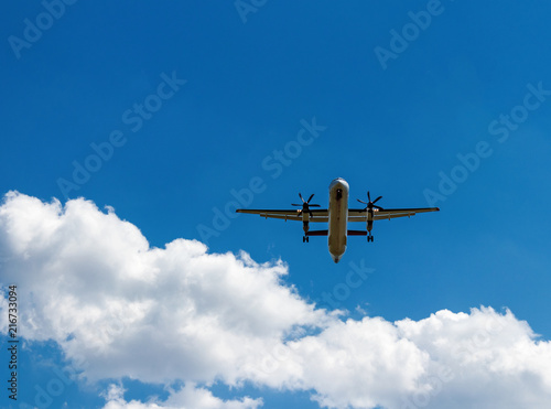 Propeller aircraft plane in clear blue sky above white clouds