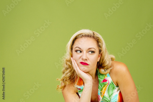 Foto Portrait of an envious woman in bad mood looking right, isolated on green studio