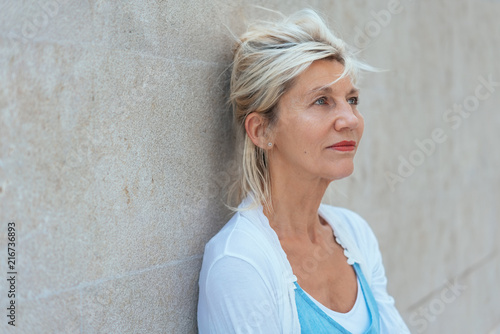 Worried woman standing thinking leaning on a wall