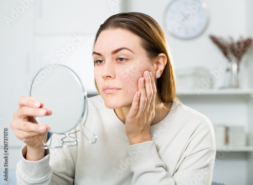 Young woman is satisfied of quality her skin in with mirror