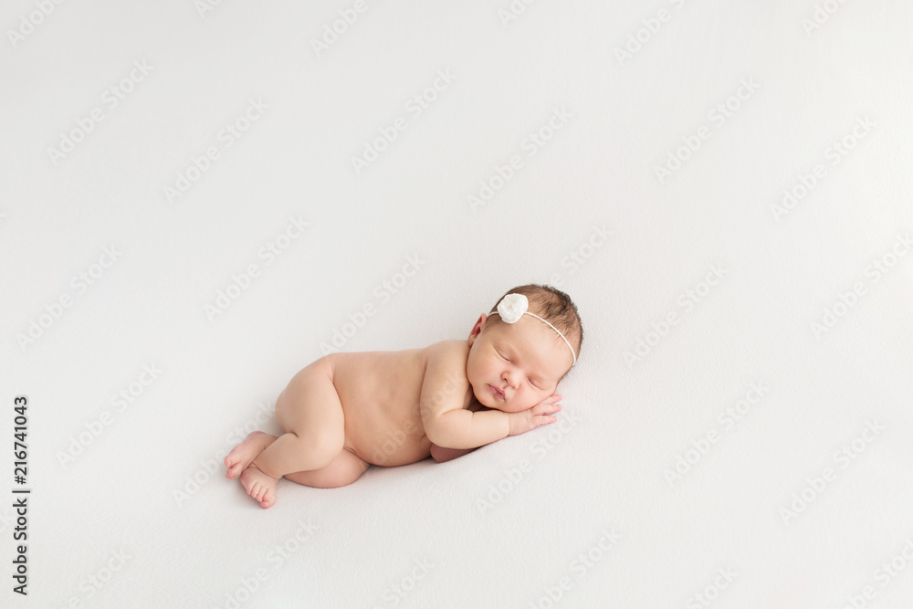 Obraz premium Sleeping newborn girl on a white background. Photoshoot for the newborn. 7 days from birth. A portrait of a beautiful, seven day old, newborn baby girl