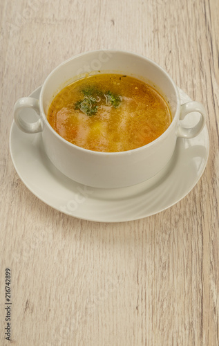 Plate with soup in a white plate on a wooden background.