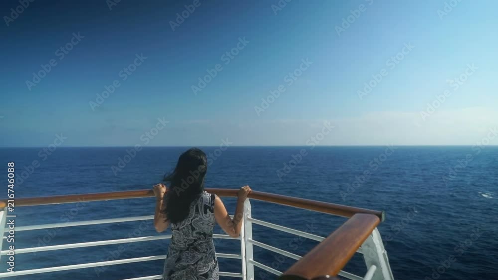 Young girl standing at front of cruise ship sailing over beautiful blue ocean. Young girl standing at front of cruise ship sailing over beautiful blue ocean.