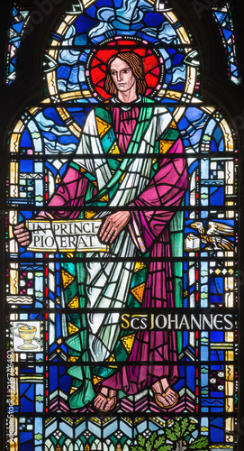 LONDON  GREAT BRITAIN - SEPTEMBER 16  2017  The St. John the Evangelist on the stained glass in church St Etheldreda by Joseph Edward Nuttgens  1952 .