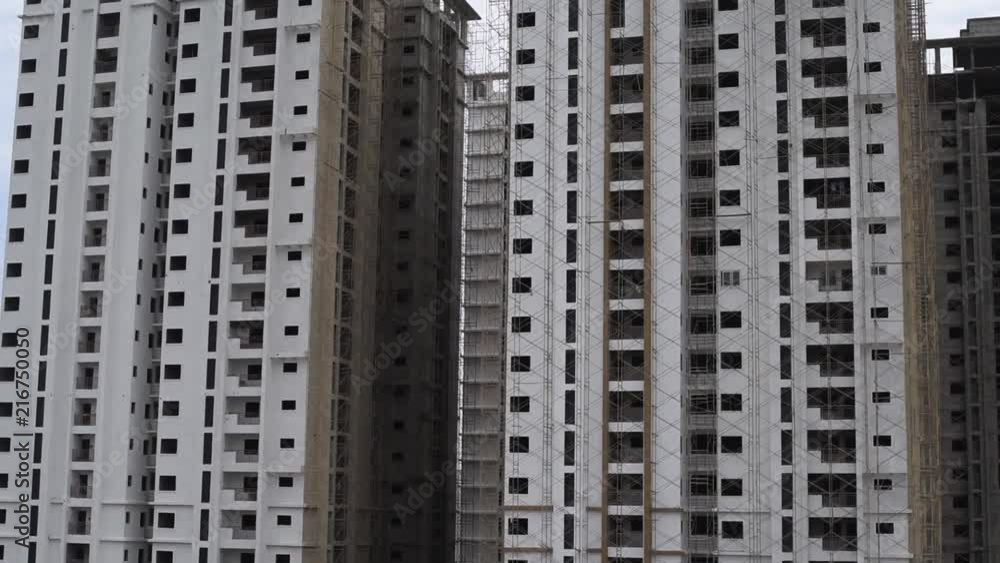 Tilt shot of a tall building under construction and traffic on road below the building Tilt shot of a tall building under construction and traffic on road below the building