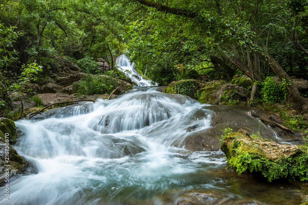 Big cascade streaming over mossy rock in green forest in long exposure Big cascade streaming over mossy rock in green forest in long exposure