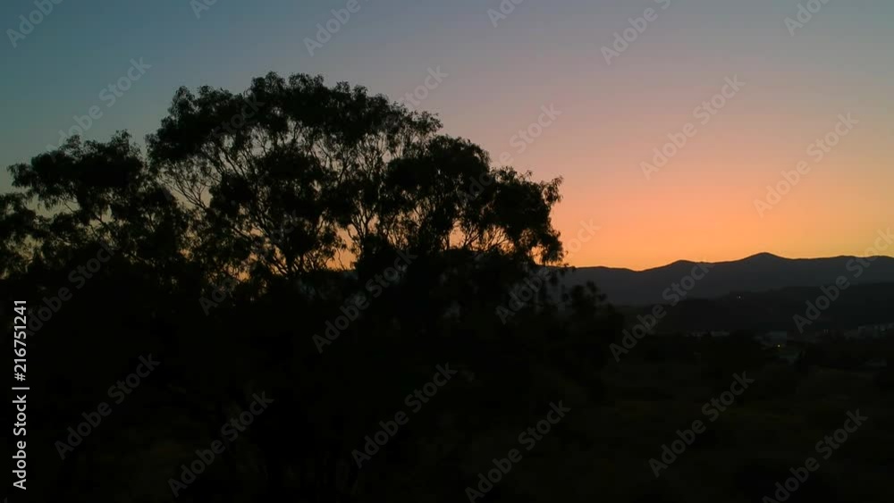 The sun descends over the mountain in Southern Spain creating rich blue, orange and red colours with large tree in foreground. The sun descends over the mountain in Southern Spain creating rich blue, orange and red colours with large tree in foreground.