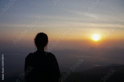silhouette alone woman seeing sunrise on top of mountain