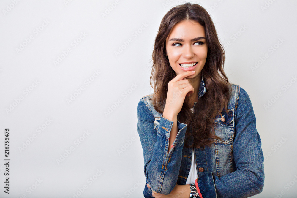 Adorable young woman with long curly hair and wonderful smile playful looking at camera dressed jeans jacket on the white background, true emotions Adorable young woman with long curly hair and wonderful smile playful looking at camera dressed jeans jacket on the white background, true emotions