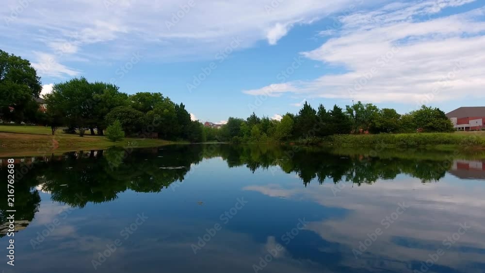 Drone flying over a small lake. Filmed in 4k on the phantom 4, blue skies and clear water, showing reflections of the clouds and trees Drone flying over a small lake. Filmed in 4k on the phantom 4, blue skies and clear water, showing reflections of the clouds and trees