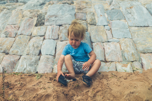Little toddler on beach putting on shoes © LoloStock