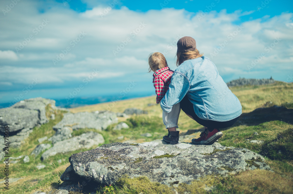 Young mother and toddler admiring view from rock on hill Young mother and toddler admiring view from rock on hill