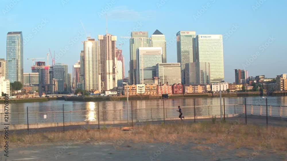 Drone shot of a man running with canary wharf as the background. Drone shot of a man running with canary wharf as the background.