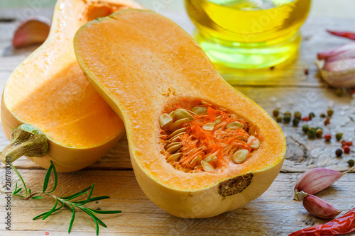 Obraz na plátne Raw organic butternut squash with ingredients for cooking on a wooden table