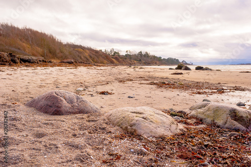 Big Rocks On Sandy Beach In Cloudy Winter Storm photo