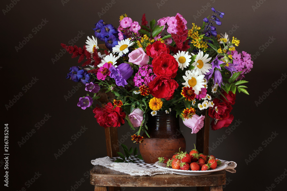 Bouquet of cultivated garden flowers and strawberries.
